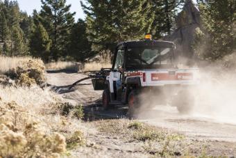 Bobcat 3650 UTV with grapple on a gravel road.