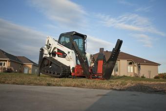Bobcat tree spade attachment is used to transplant a tree by a residential sidewalk.