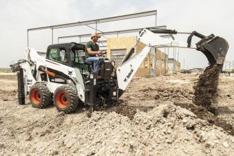 Bobcat S530 skid-steer loader with backhoe attachment digging a trench.