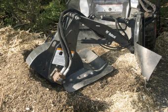 Large tree stump is pulverized by Bobcat stump grinder attachment.