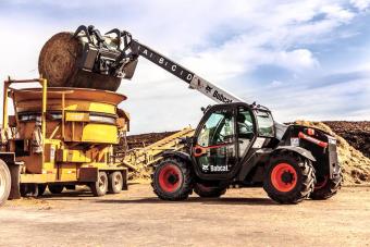 The VersaHANDLER V519 telehandler extends its boom to place a hay bale.